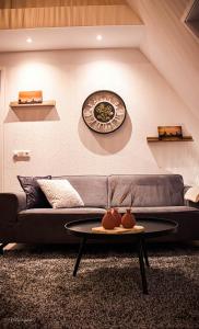 ein Wohnzimmer mit einer Couch und einer Uhr an der Wand in der Unterkunft Appartement de 3 haasjes in landelijke omgeving. in Wijdenes