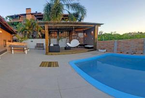 a swimming pool in a backyard with a gazebo at Bangalôs do Rosa-Praia do Rosa in Imbituba