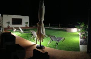 a group of chairs and an umbrella on a lawn at Casa Percea in Mazo