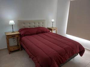 1 dormitorio con 1 cama roja y 2 mesitas de noche en ALOHA en Sierra de la Ventana