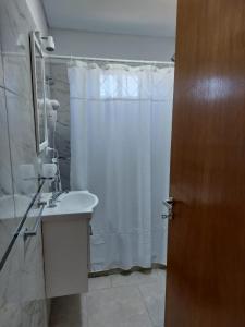 Un baño con una cortina de ducha blanca y un lavabo. en ALOHA, en Sierra de la Ventana