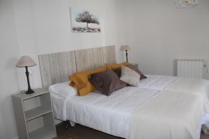 una camera da letto con un grande letto bianco con cuscini di Serendipia ad Ávila