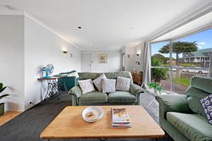 ein Wohnzimmer mit einem Sofa und einem Tisch in der Unterkunft Lagoon Haven - Waikanae Holiday Home in Paraparaumu Beach
