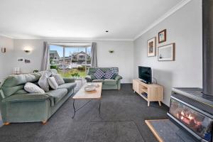 uma sala de estar com dois sofás e uma lareira em Lagoon Haven - Waikanae Holiday Home em Paraparaumu Beach