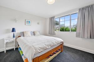 um quarto com uma cama grande e uma janela em Lagoon Haven - Waikanae Holiday Home em Paraparaumu Beach