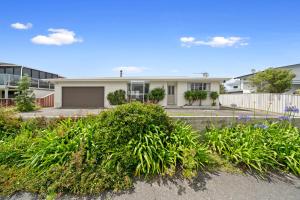 uma casa branca com plantas à frente em Lagoon Haven - Waikanae Holiday Home em Paraparaumu Beach