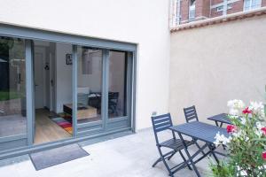 a patio with a table and chairs and a sliding glass door at Le Saint-Germain - Porte d'Orléans - Cité Universitaire Paris 14 in Gentilly