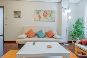 a living room with a couch with orange and blue pillows at Luminoso y acogedor apartamento con wifi in Gijón