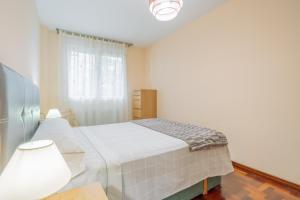 a white bedroom with a bed and a window at Luminoso y acogedor apartamento con wifi in Gijón