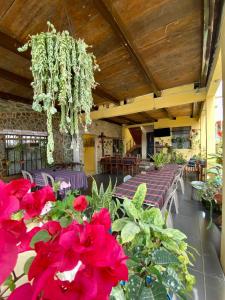 een kamer met tafels en rode bloemen en een kroonluchter bij El Calvario Hostal in Cobán