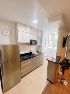 eine Küche mit einem Kühlschrank aus Edelstahl und einer Mikrowelle in der Unterkunft [H] Holtin estándar en Piura in Piura