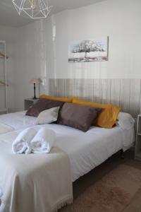 1 cama grande con sábanas blancas y almohadas. en Serendipia, en Ávila