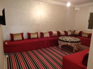 - un salon avec un canapé rouge et une table dans l'établissement Belles appartements à côté de la plage Tamehrouchte, à Mirleft