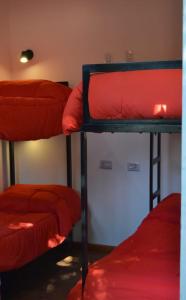 three bunk beds in a room with red sheets at Complejo turístico Nahuel pan in Esquel