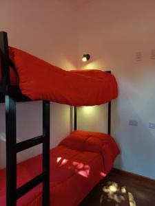 a bedroom with two bunk beds with red sheets at Complejo turístico Nahuel pan in Esquel