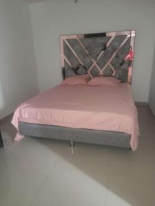 1 cama con sábanas rosas y cabecero de madera en CASA AMOBLADA EN CONJUNTO CERRADO, en Cúcuta