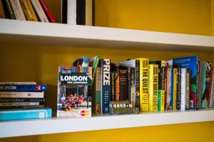 a shelf full of books on a yellow wall at Elegant and Peaceful 2BD apt - Barons Court/London in London