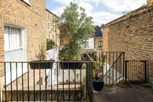 a gate with plants in pots next to a brick building at Elegant and Peaceful 2BD apt - Barons Court/London in London