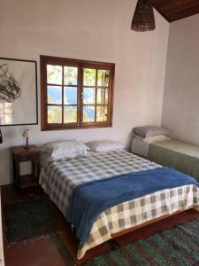 1 dormitorio con cama y ventana en Casa da Serra en Delfim Moreira
