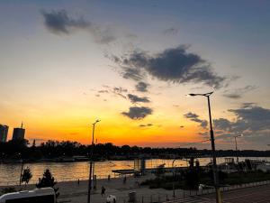 a sunset over a body of water with a street light at Loft Sava View Old Town Renovated in Belgrade