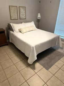 a bedroom with a white bed with a tiled floor at Hidden Treasure in Longview