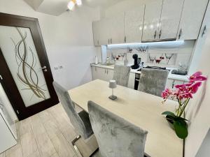 een keuken met een tafel en stoelen en een keuken met witte kasten bij Dacia Residence Apartments Self Check-in in Craiova