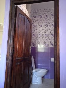 een badkamer met een toilet en een houten deur bij Ourika in Ourika