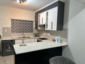a kitchen with white cabinets and a washer and dryer at Canal View Estate & Resort in Manzini