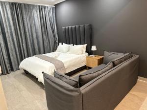 - une chambre avec un lit et un canapé dans l'établissement Canal View Estate & Resort, à Manzini