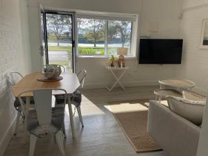 a living room with a table and a tv at The Wheelhouse - 2BR Waterfront Apt in town in Lakes Entrance
