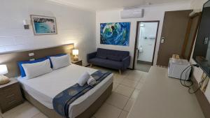 a bedroom with a bed and a blue chair at Moffat Beach Motel Caloundra in Caloundra