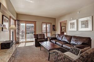 ein Wohnzimmer mit einem Ledersofa und einem Tisch in der Unterkunft Ski In-Out Village at Breckenridge Condo in Breckenridge