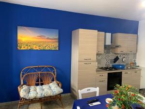 a kitchen with a blue wall with a chair and a table at A Rizzilla Guest House in Nicotera Marina