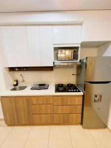 uma cozinha com armários brancos e um frigorífico de aço inoxidável em [H] Natural Holtin at Piura em Piura