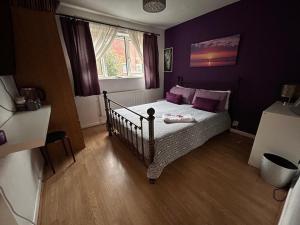 1 dormitorio con 1 cama con paredes de color púrpura y ventana en Home from home, close to Redditch hospital & transport links en Redditch