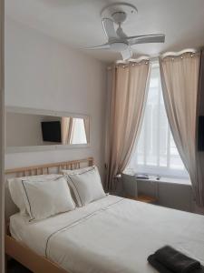 a bedroom with a bed with a ceiling fan and a window at Engineer Lane House in Gibraltar