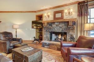 a living room with a stone fireplace and leather furniture at Luxurious 2 Bedroom Condo 50 Feet From The Slopes! condo in Beaver Creek