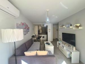 ein Wohnzimmer mit einem lila Sofa und einem TV in der Unterkunft Apartamento Luna de Zahara - Situado en la zona tranquila del pueblo a 3 min de la playa y ocio in Zahara de los Atunes