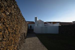 uma parede de pedra em frente a uma casa em ENTRE MUROS - Turismo Rural - Casa com jardim e acesso direto ao mar na Ribeira Grande