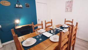 a dining room with a wooden table with plates and wine glasses at Stourbridge House, Luxurious 3 Bedrooms - Ideal Location for Contractors and Families, Free Parking, Fast Wifi, Sleeps up to 8 in Lye