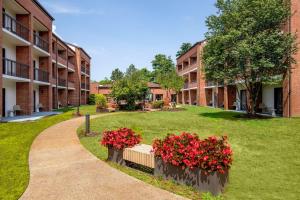 a courtyard of an apartment building with red flowers at Sonesta Select Boston Foxborough Mansfield in Foxborough