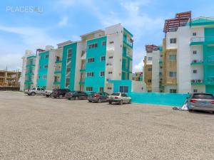 a row of buildings with cars parked in a parking lot at Hermoso apartamento 1 hab a pasos de la playa in Punta Cana