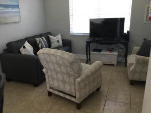 - un salon avec un canapé, une chaise et une télévision dans l'établissement Madeira Bonita Apartment #6, à St. Pete Beach