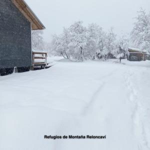 a snow covered yard with a building and trees at Refugios de Montaña Reloncaví - Ruka Lee I in Las Trancas