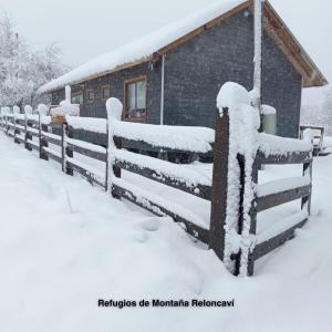 a fence covered in snow next to a building at Refugios de Montaña Reloncaví - Ruka Lee I in Las Trancas