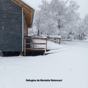 um banco coberto de neve ao lado de um edifício em Refugios de Montaña Reloncaví - Ruka Lee I em Valle Las Trancas