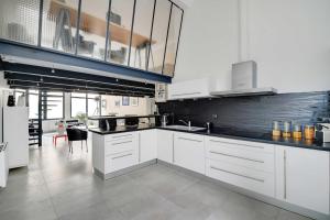 une cuisine avec des placards blancs et un comptoir noir dans l'établissement Amazing loft, à Pantin