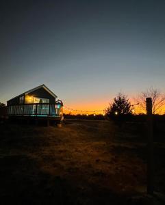 Ein Haus auf einem Feld mit Sonnenuntergang im Hintergrund in der Unterkunft Lazy Spring Farm 