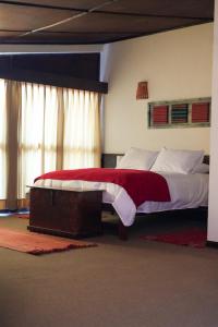 um quarto com uma cama grande e um cobertor vermelho e branco em Hotel Pilancones em Cajamarca