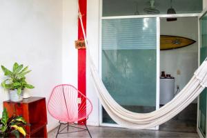 um quarto com uma rede de descanso, uma cadeira e uma janela em Casa Daikiri em Puerto Escondido